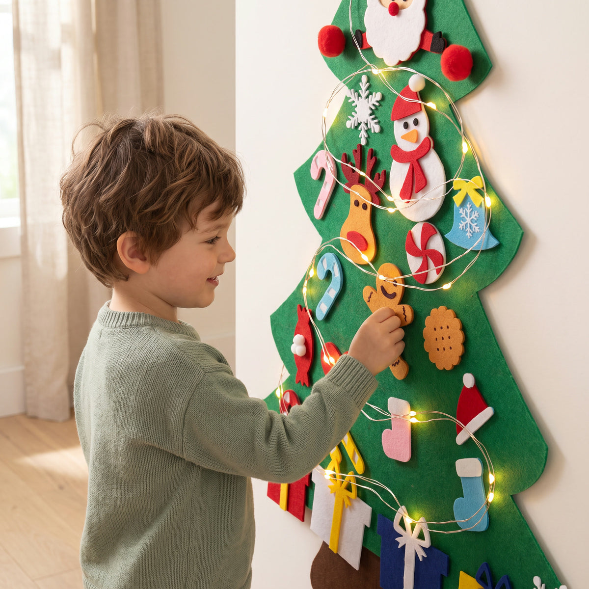 Boy pressing a felt gingerbread man onto his felt Christmas tree